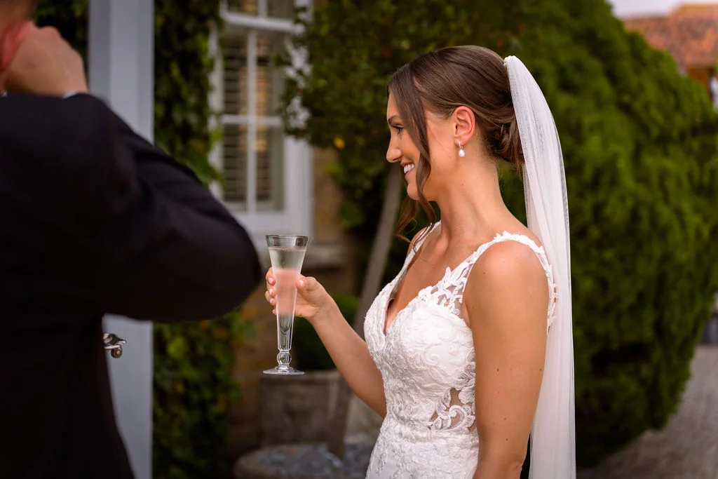 A bride and groom holding a glass of champagne.