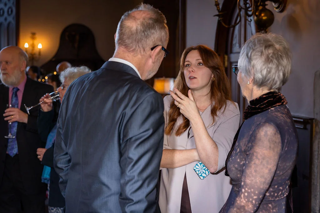 Wedding guests mingling and chatting during the drinks reception inside an elegant venue.
