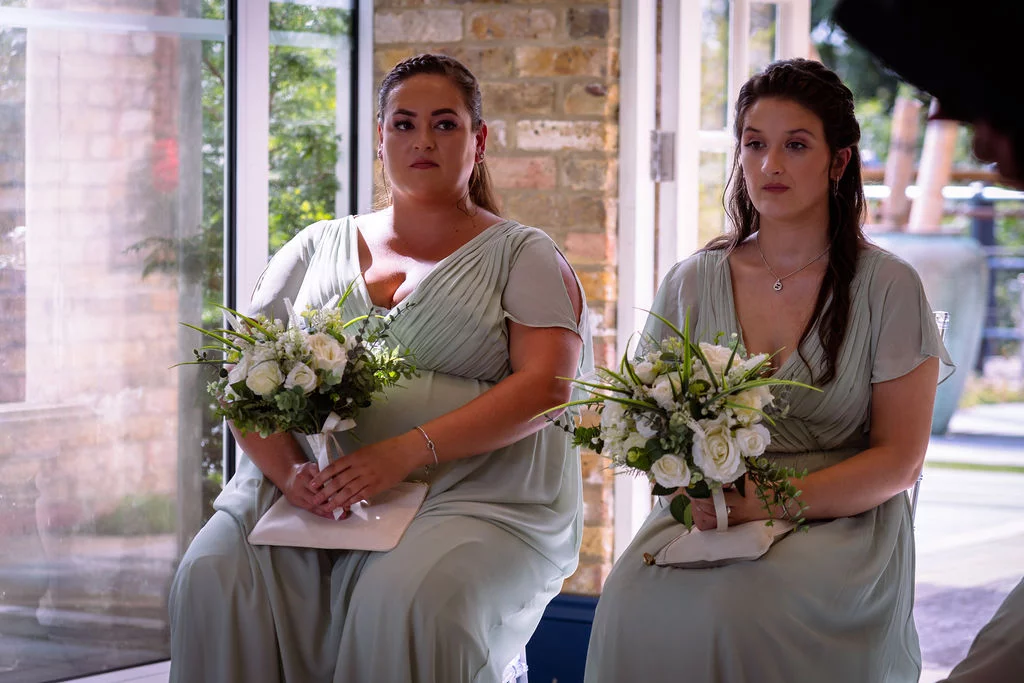 Two bridesmaids sitting in front of a window.