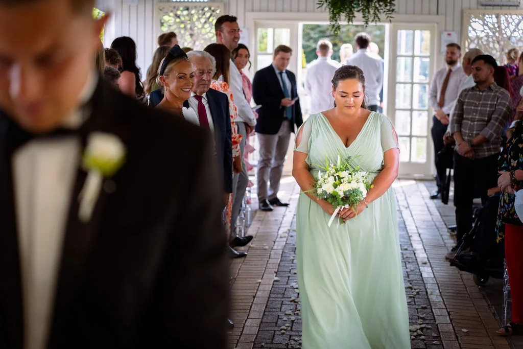 A bride walking down the aisle in a green dress.