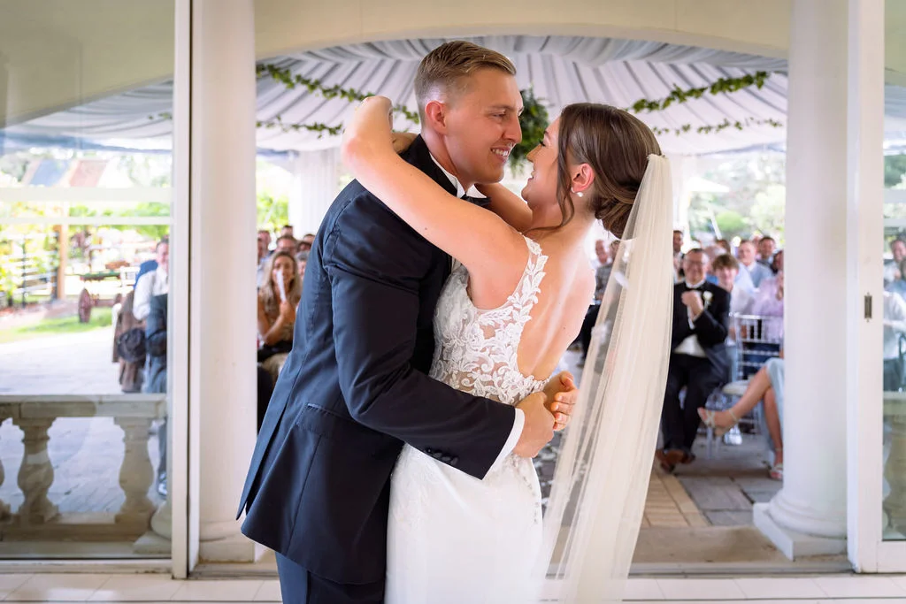 A bride and groom share their first dance in front of their guests.