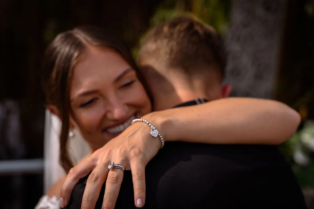 A bride and groom hugging in front of a tree.
