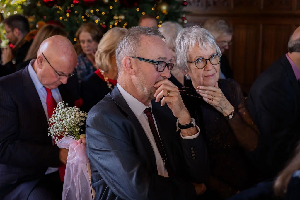 An older couple in the congregation look emotional and tearful during the wedding ceremony.