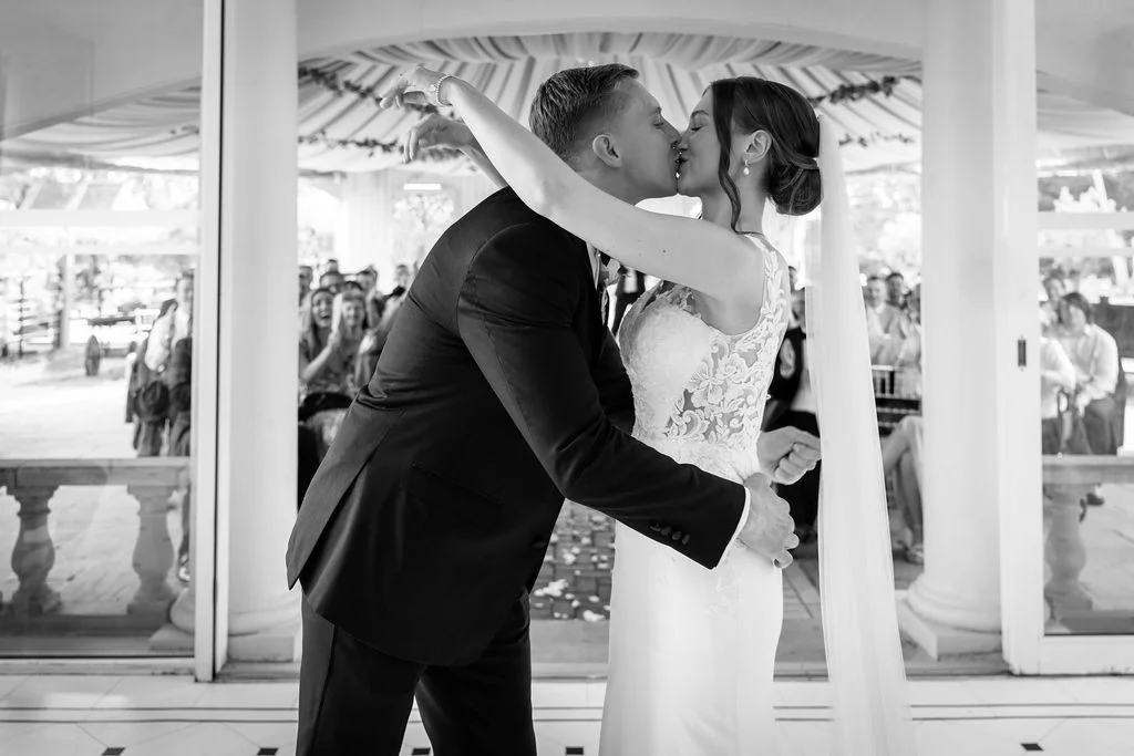 A bride and groom kissing in front of a gazebo.