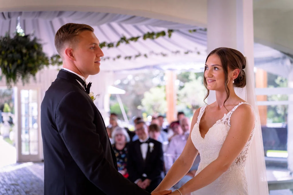 A bride and groom holding hands during their wedding ceremony.