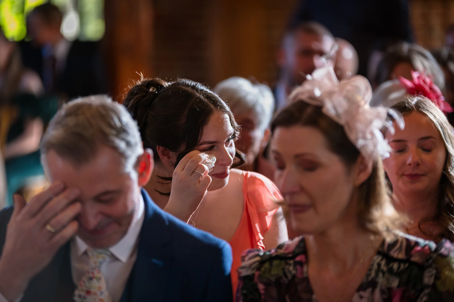 Emotional wedding guests shed happy tears during a heartfelt ceremony, captured in a candid and tender moment.