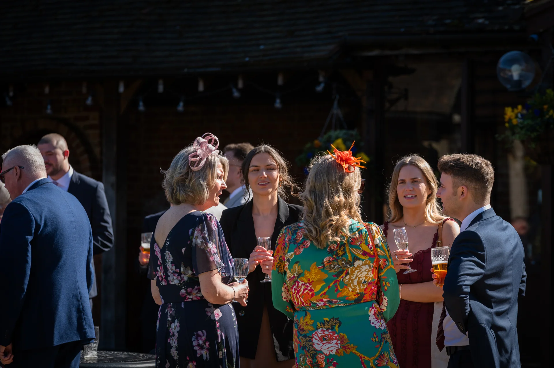 Wedding guests mingle and enjoy drinks outside in the sunshine during the reception.