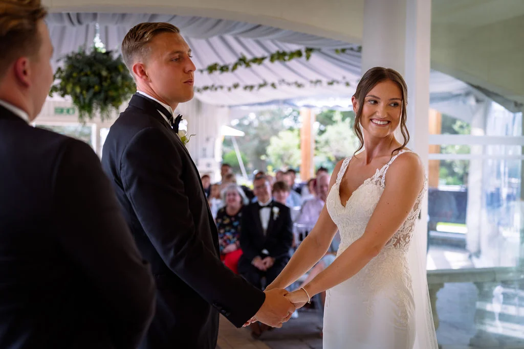 A bride and groom holding hands during their wedding ceremony.