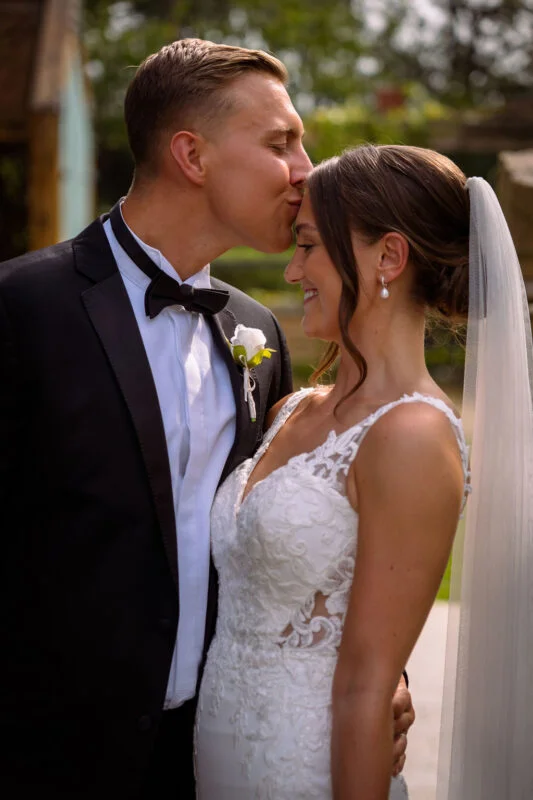 A bride and groom kissing in front of a stone wall.