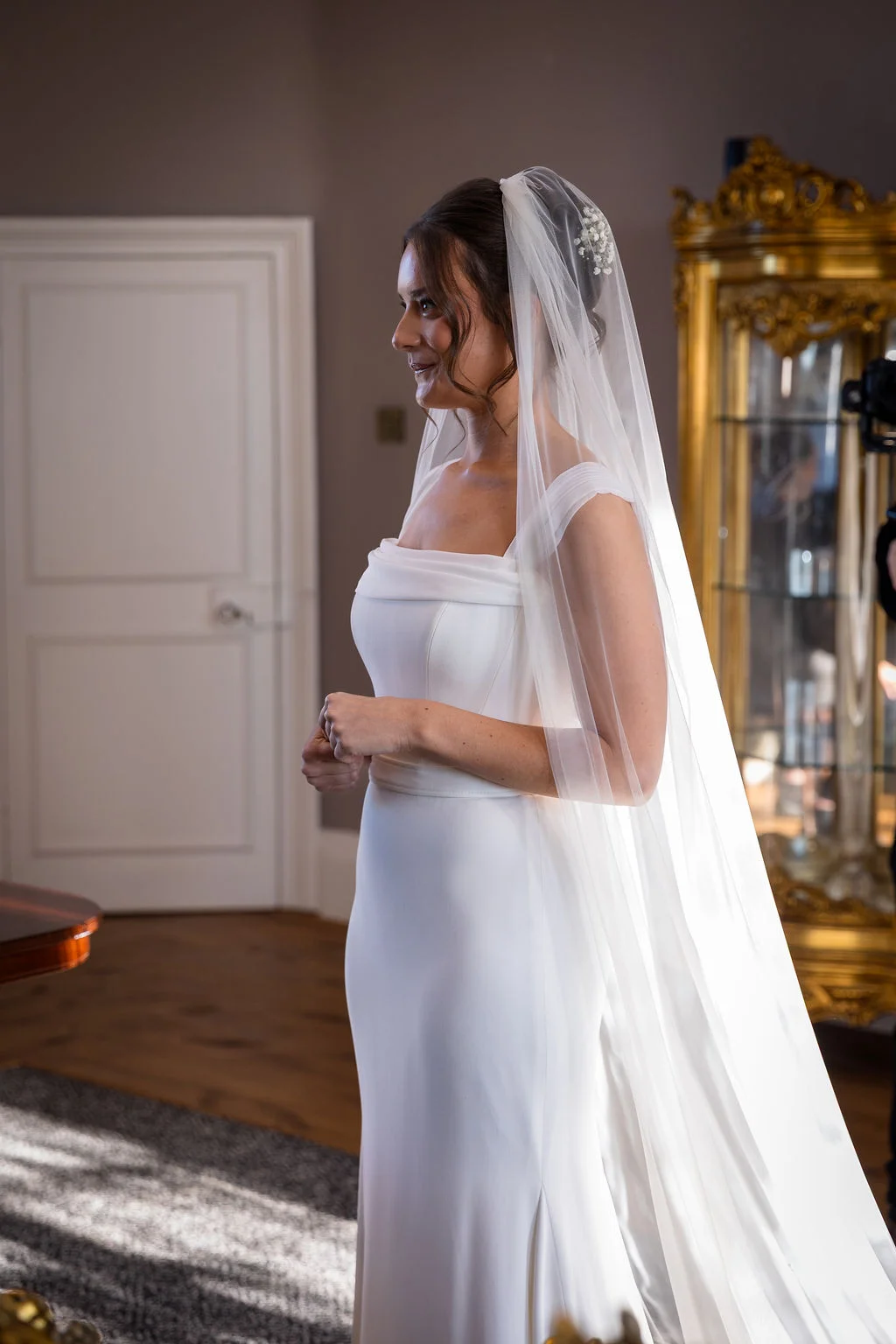 A stunning solo portrait of a radiant bride wearing a sleek a-line crepe wedding dress with a square neckline and a long cathedral veil.