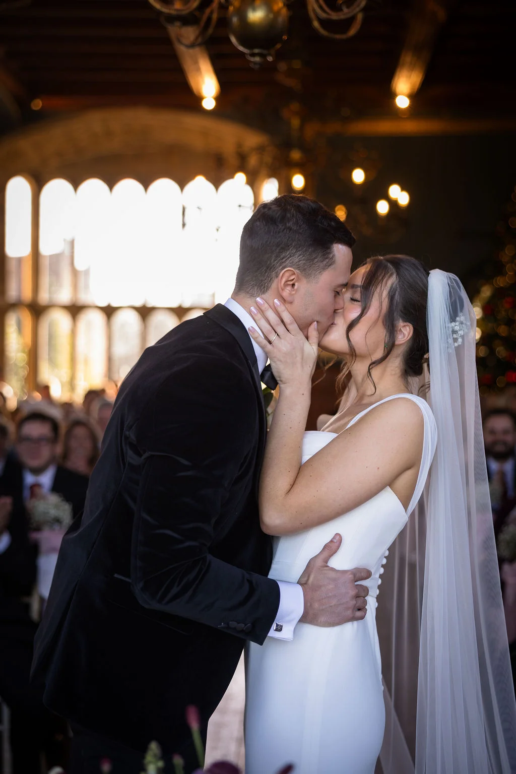 Newlywed bride and groom share their first kiss at the altar inside a historic church with warm interior lighting.