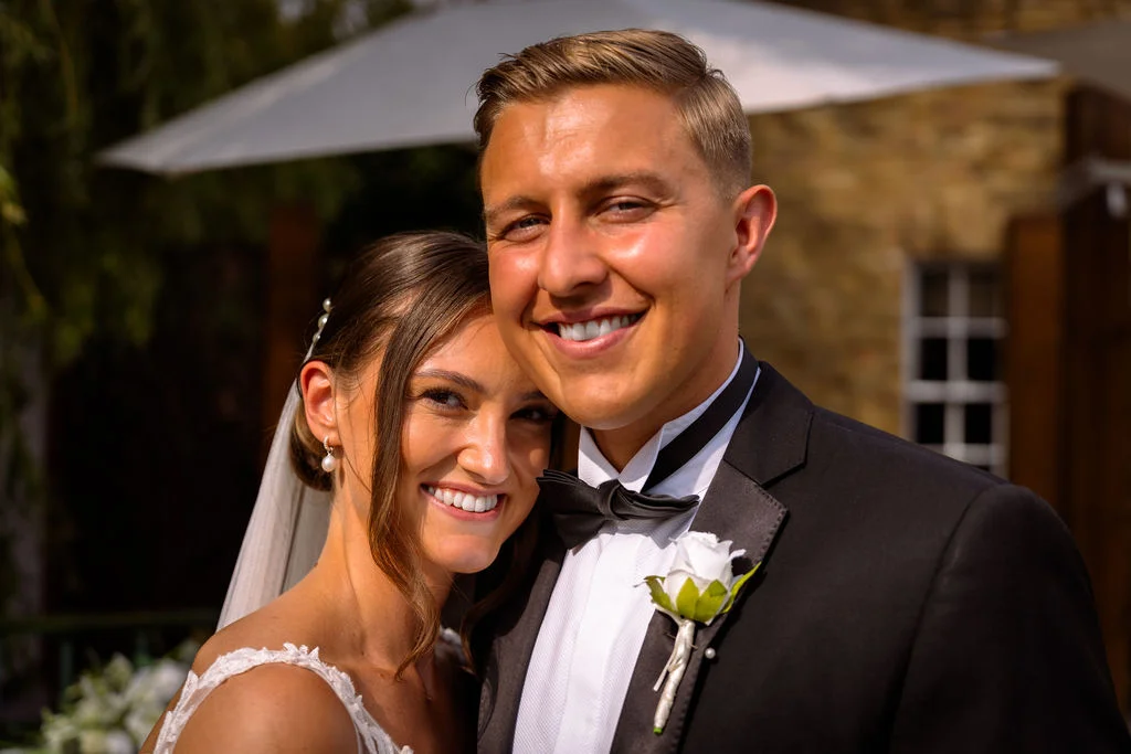 A bride and groom posing for a photo in a tuxedo.