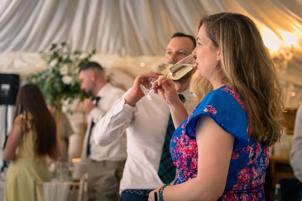 Wedding guests enjoy drinks and conversation inside a draped marquee during the reception.
