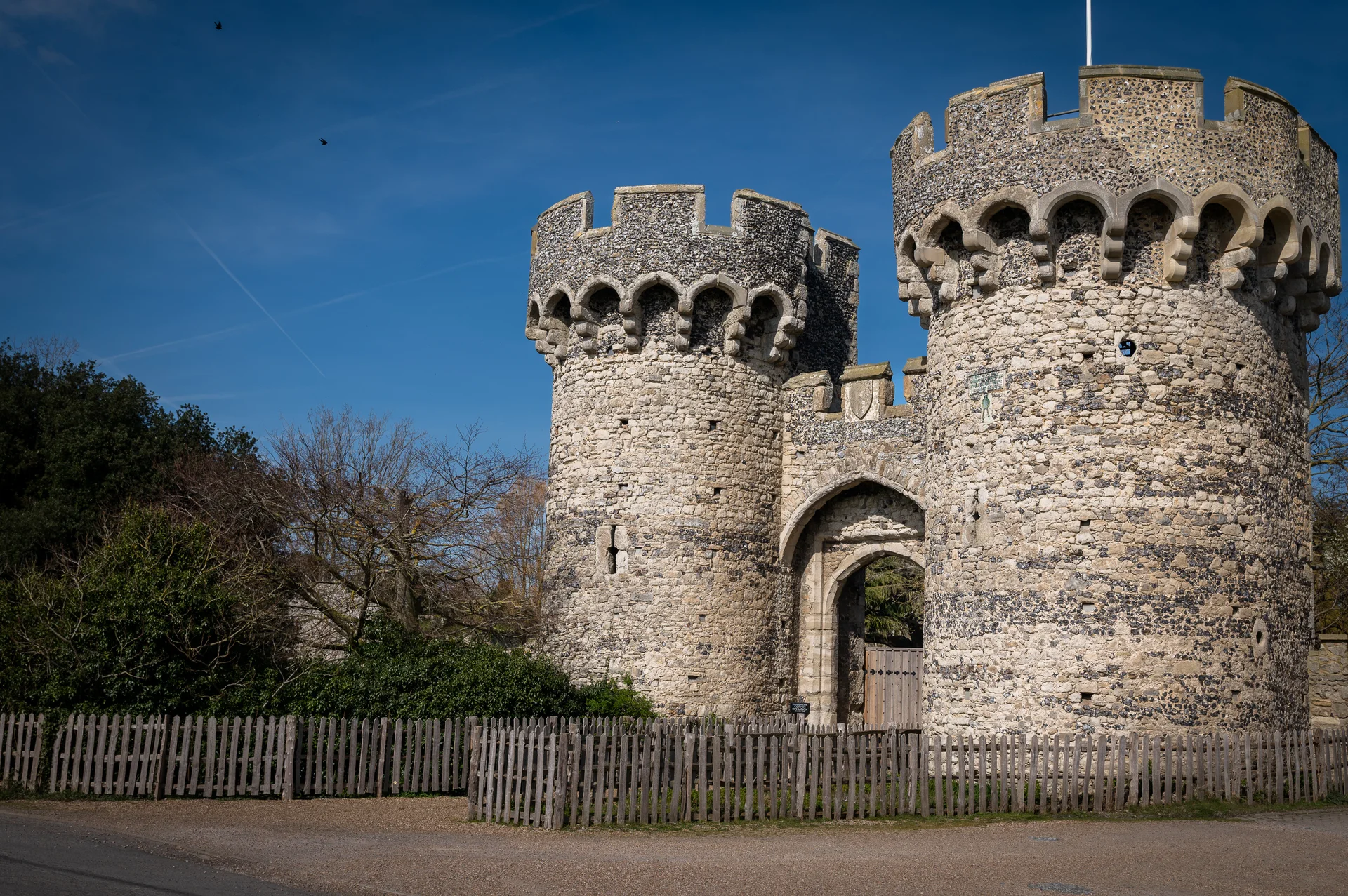 The imposing stone gatehouse and twin towers of a historic castle wedding venue stand proudly under a clear blue sky.