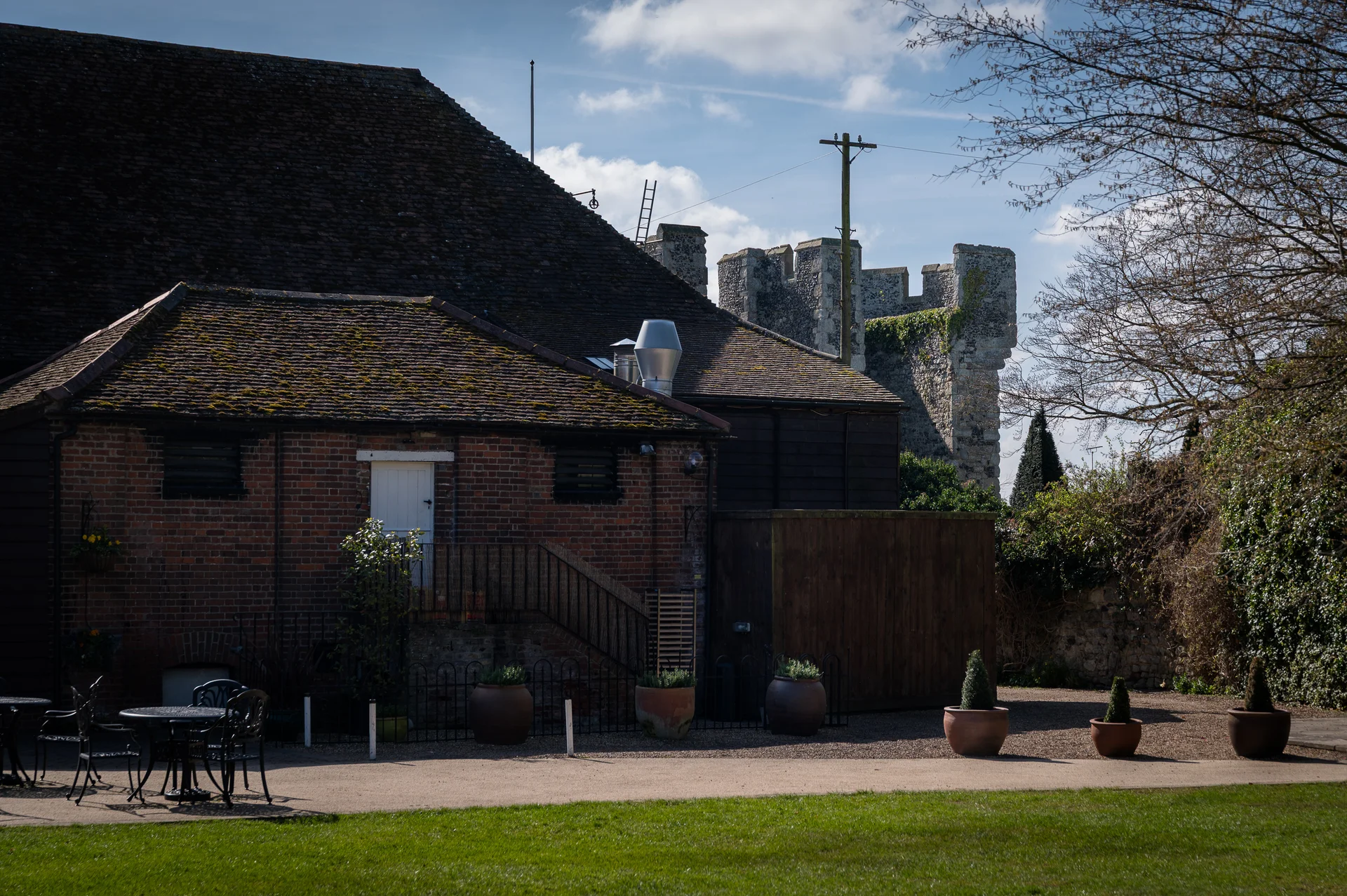 A historic wedding venue featuring a red brick building and ancient stone castle ruins under a bright blue sky on a sunny day.