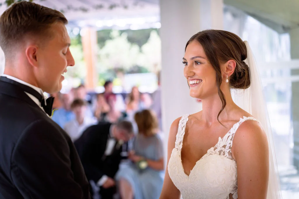 A bride and groom smile at each other during their wedding ceremony.