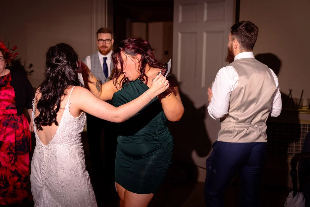Guests and the bride energetically dance together on the evening reception dance floor under direct flash lighting.