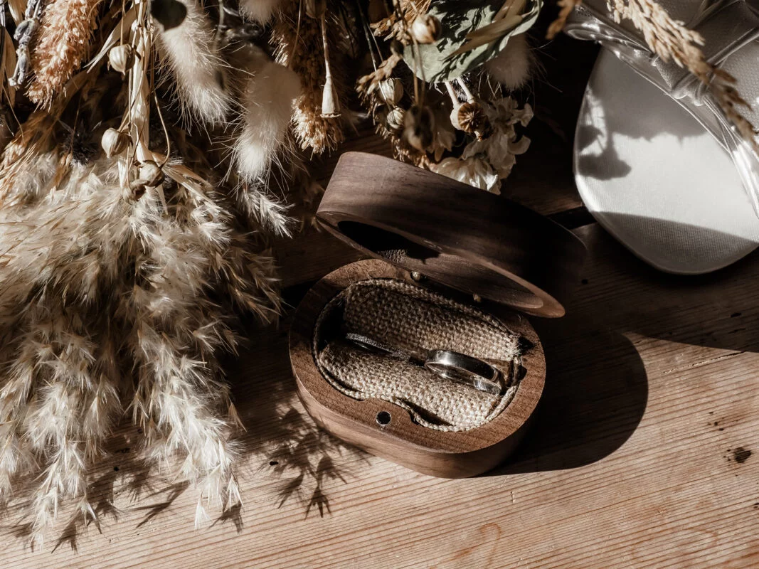 A wedding ring in a wooden box on a wooden table.