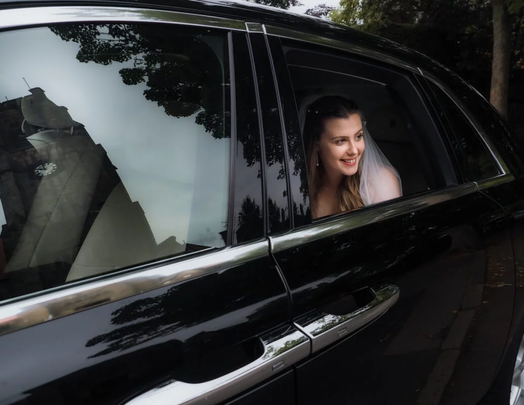 A bride looking out of the window of a car.