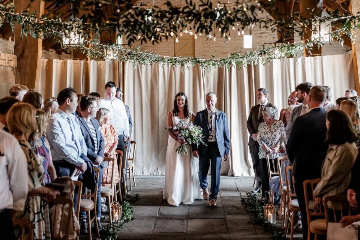 A bride and groom walking down the aisle at a barn wedding.