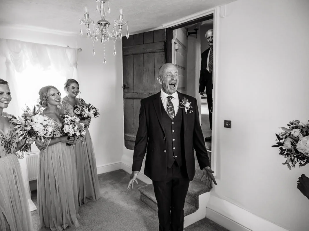 A man in a suit walks down the aisle with his bridesmaids.
