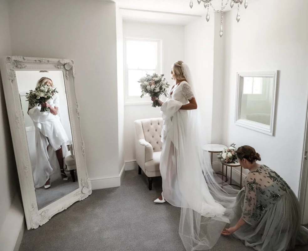 A bride getting ready in a room with a mirror.