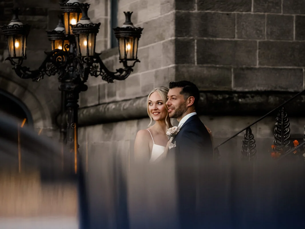 A bride and groom standing in front of a lamp post.