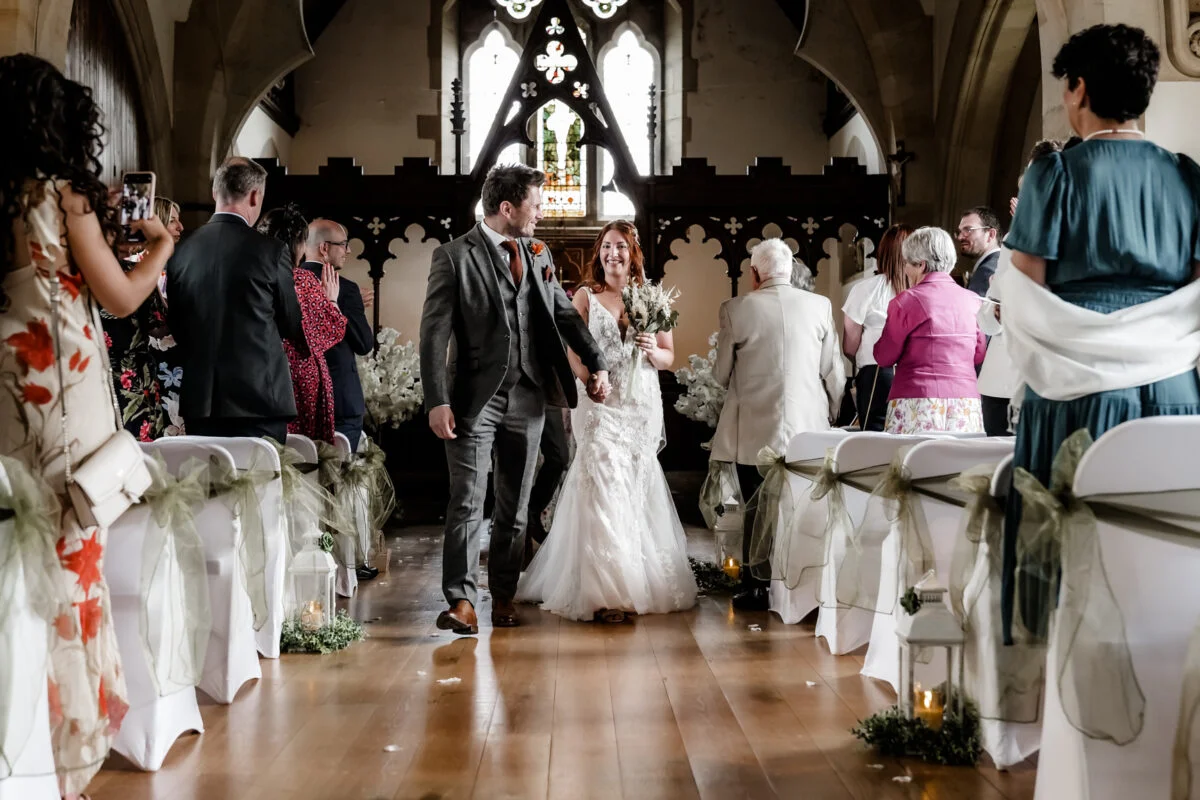 A bride and groom walking down the aisle of a church.