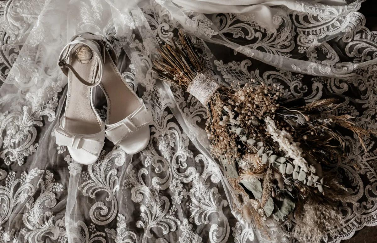 A wedding dress and shoes are laid out on a table.