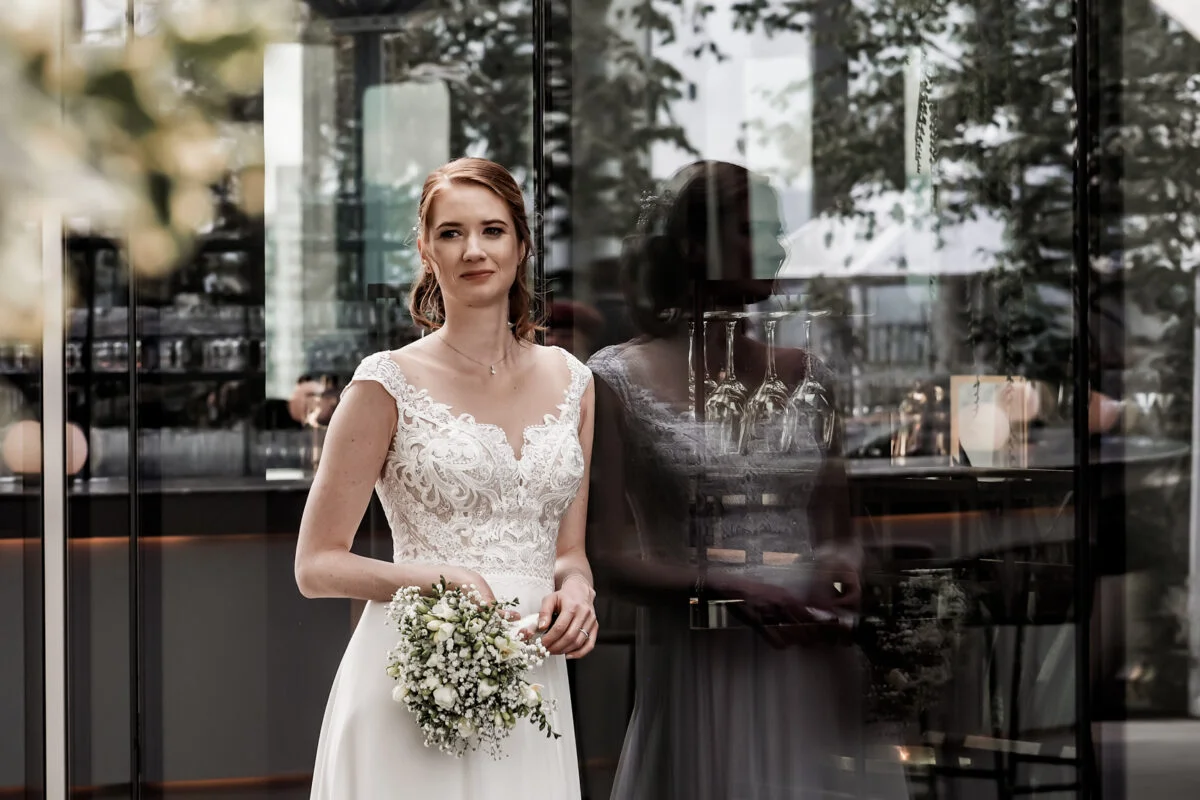 A bride in a wedding dress standing in front of a glass door.