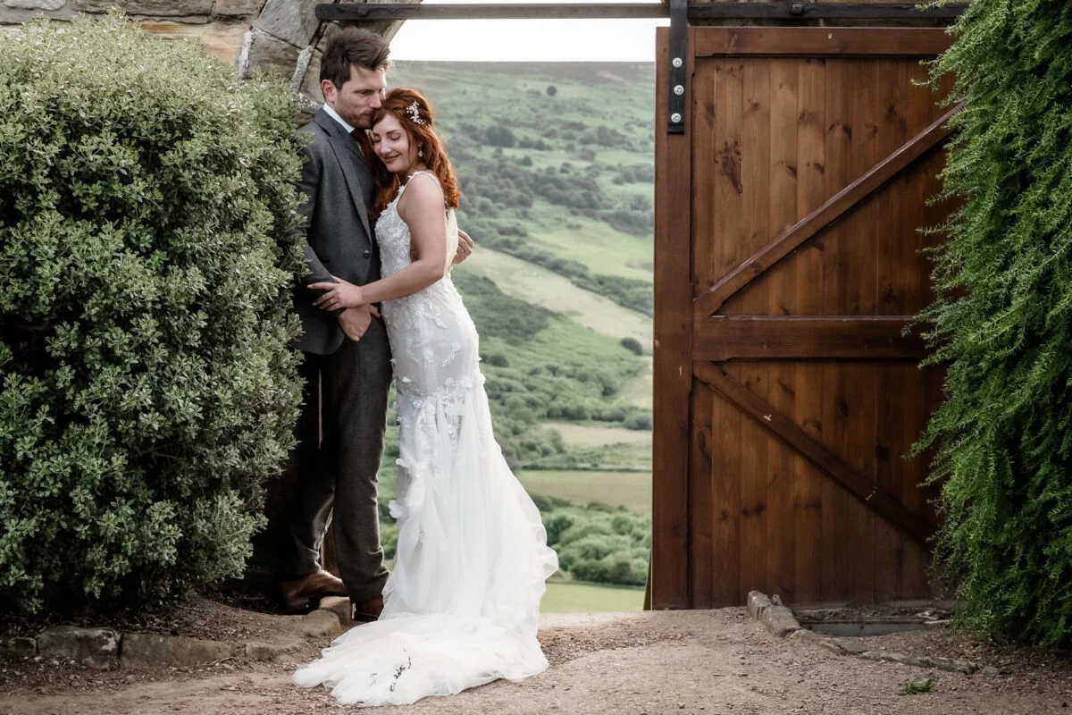A bride and groom posing in front of a wooden door.