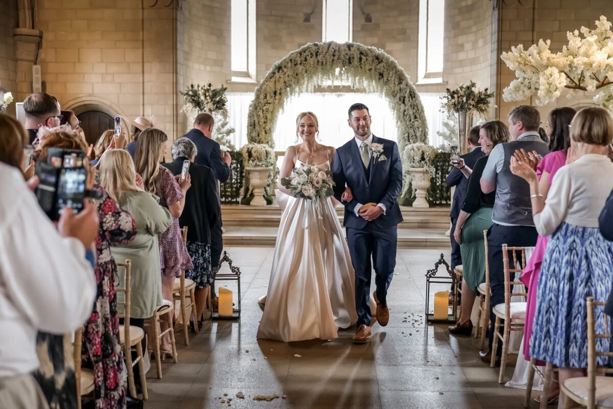 A bride and groom walking down the aisle at a wedding ceremony.