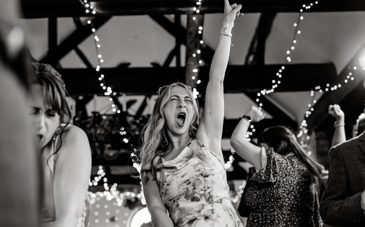 Black and white photo of a woman dancing at a wedding.
