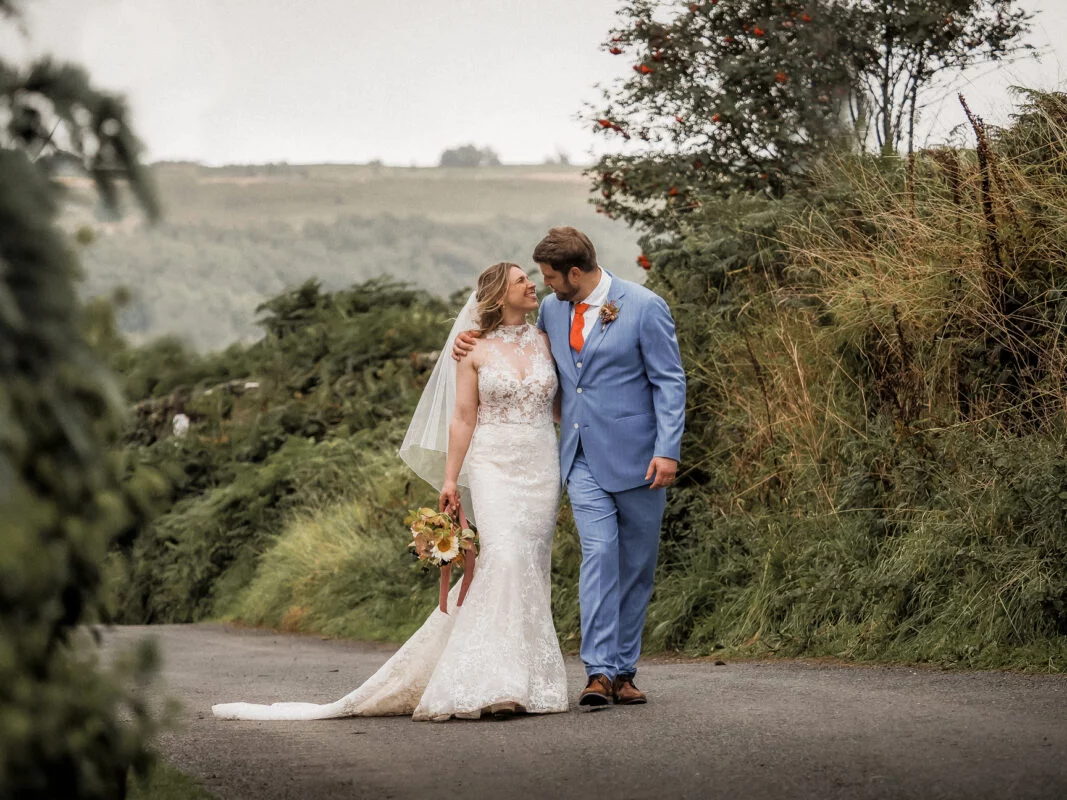 A bride and groom kissing on a country road.