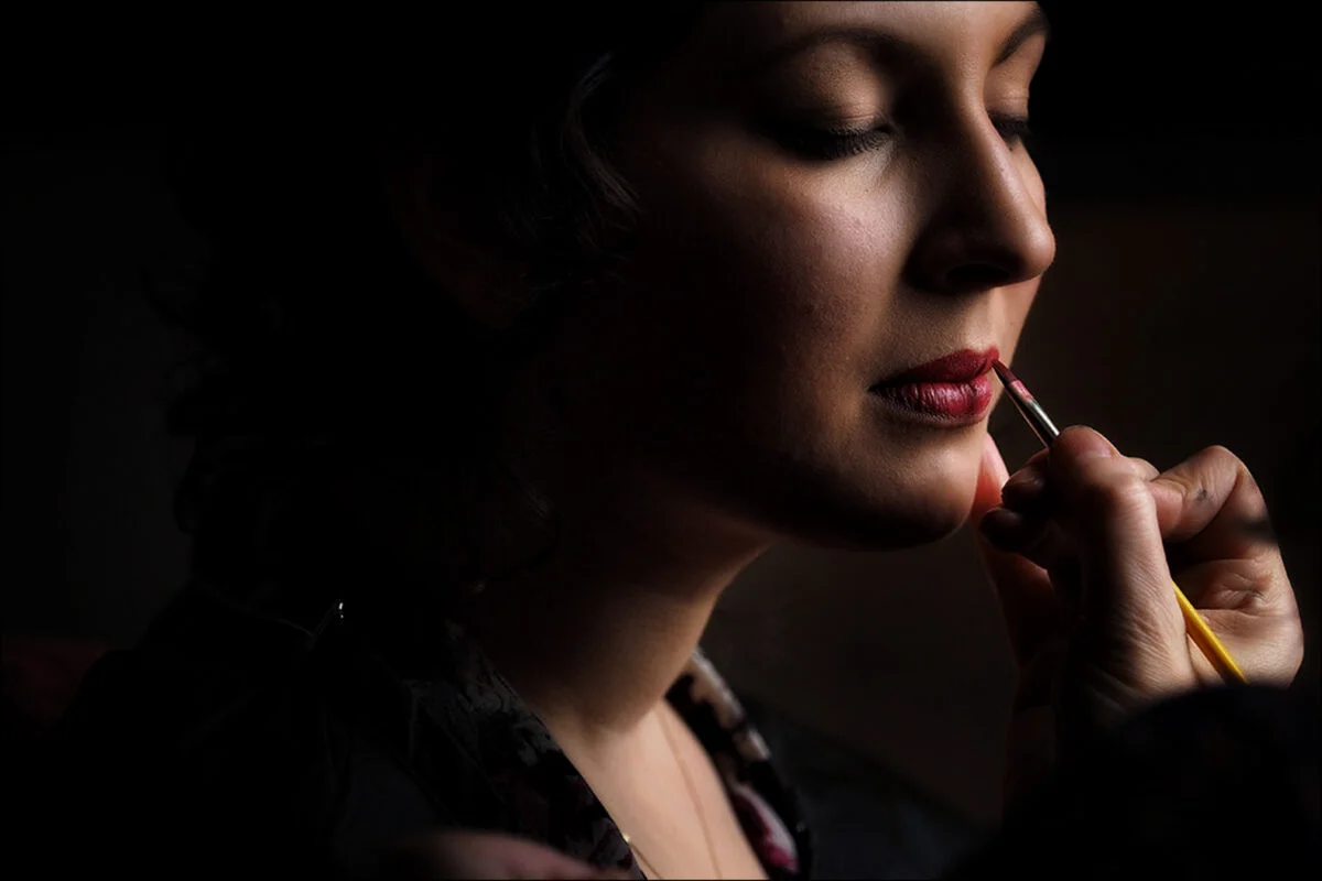 A woman is getting her makeup done by a makeup artist.