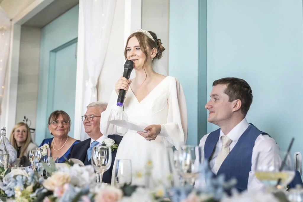 A bride speaking into a microphone at a wedding reception.