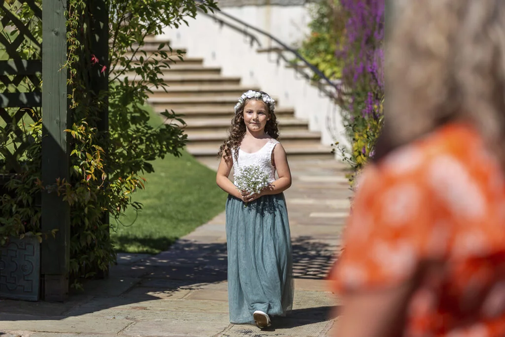 A little girl walking down a path with a flower in her hair.