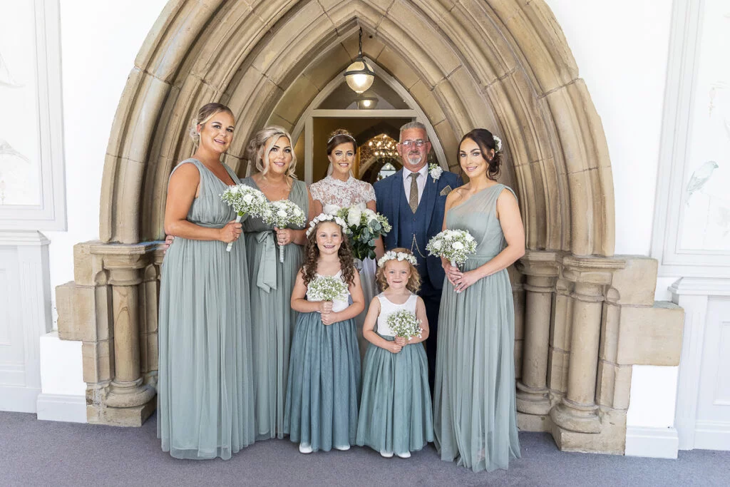 A bride and her bridesmaids pose in front of an archway.