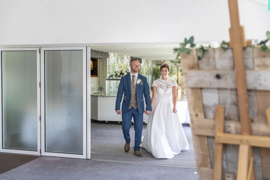 A bride and groom walking through a glass door.