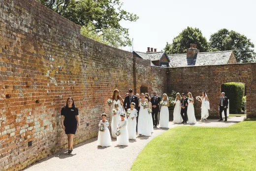 A group of wedding party standing in front of a brick wall.