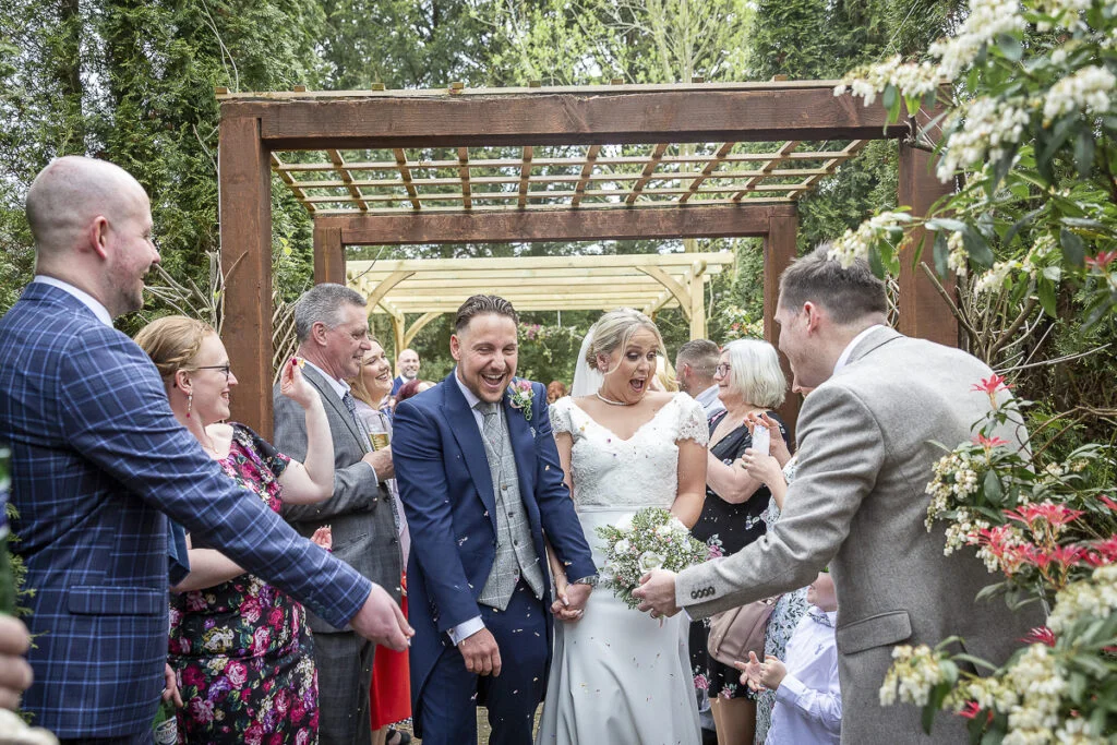 A bride and groom walk down the aisle at a garden wedding.