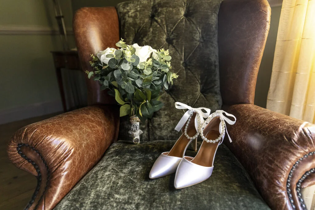 A pair of white shoes and a bouquet sit on a chair.