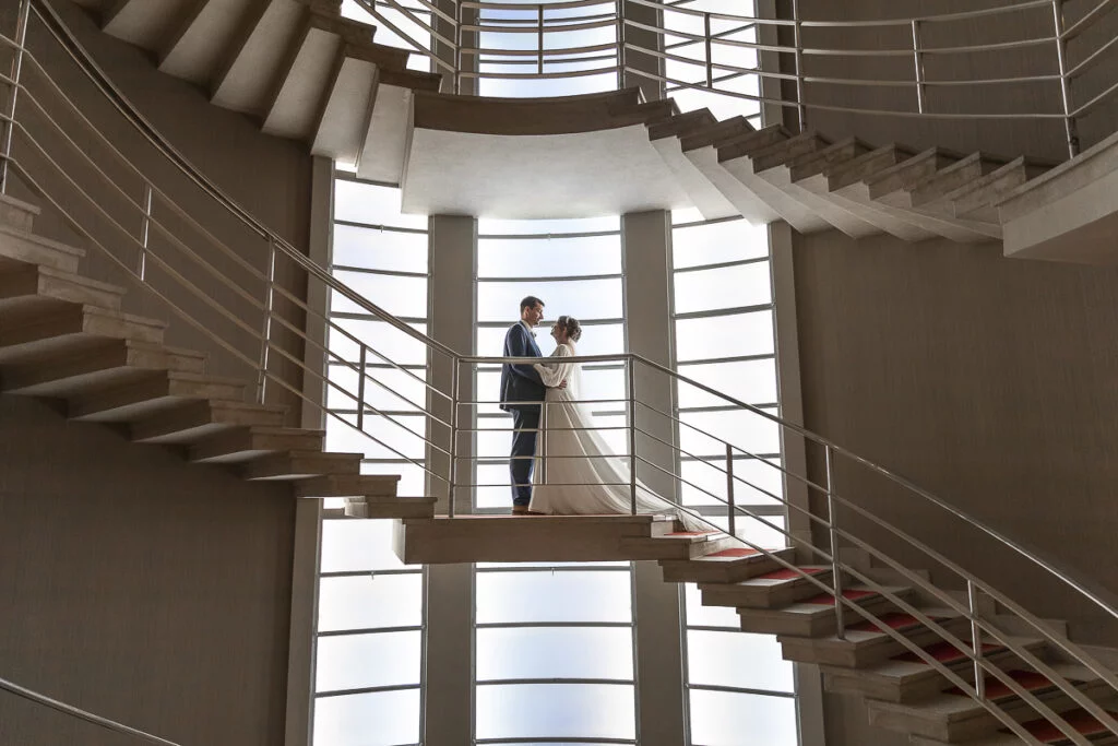 A bride and groom standing on a spiral staircase.