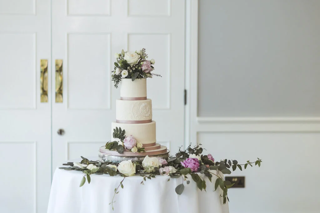 A wedding cake on a table in front of a door.