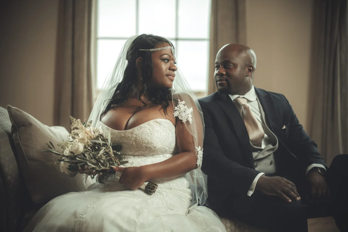 A bride and groom sitting on a couch.