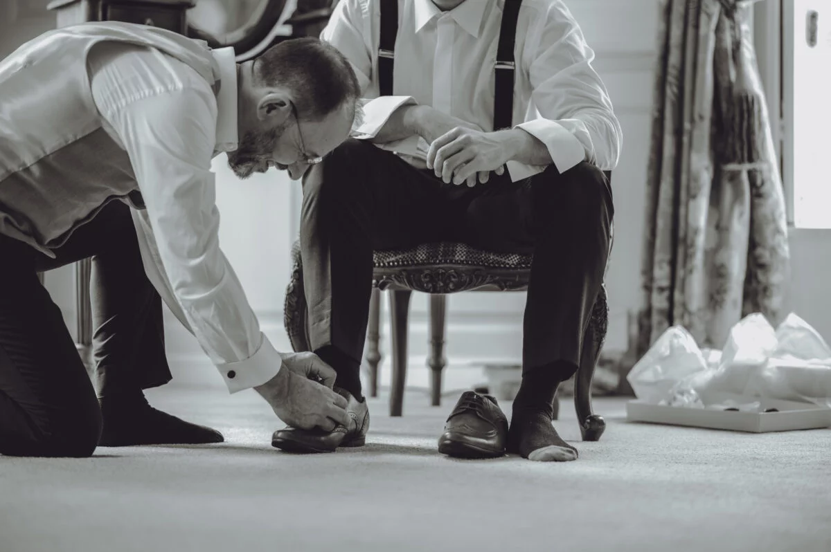 Two men putting on their shoes in a room.