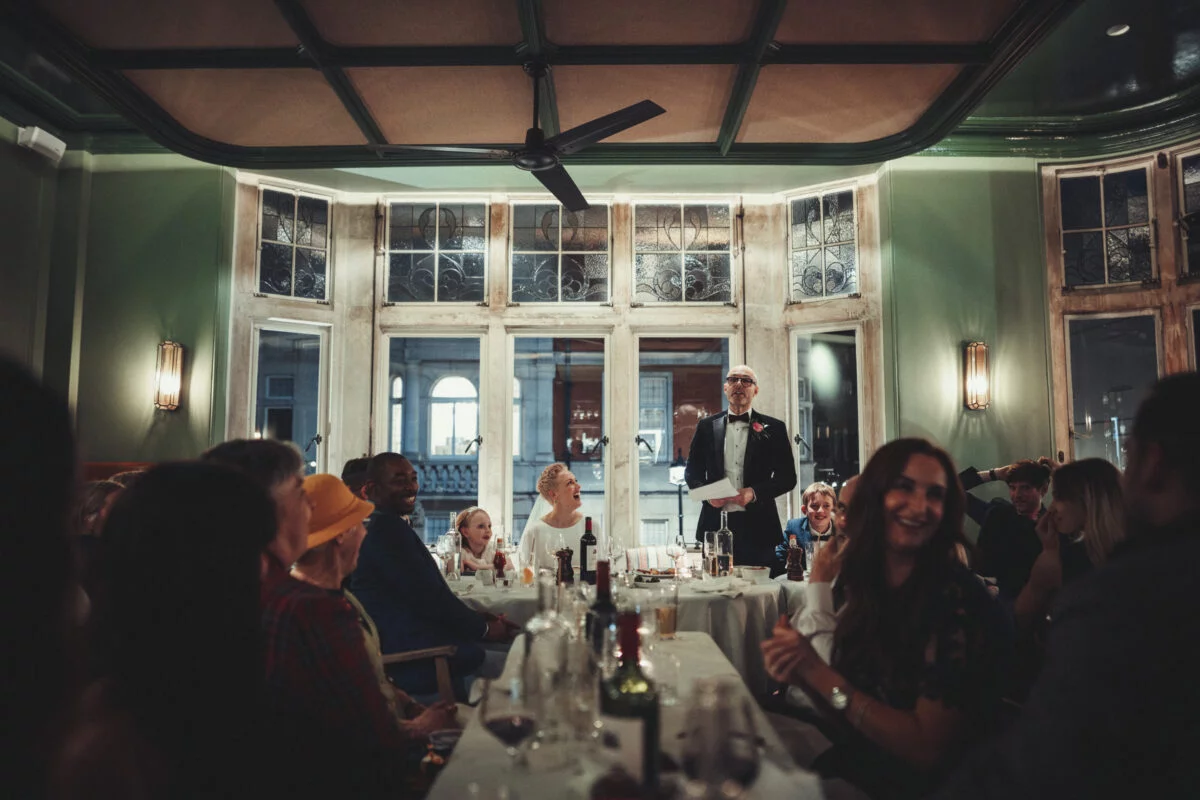 A man speaking to a group of people in a restaurant.