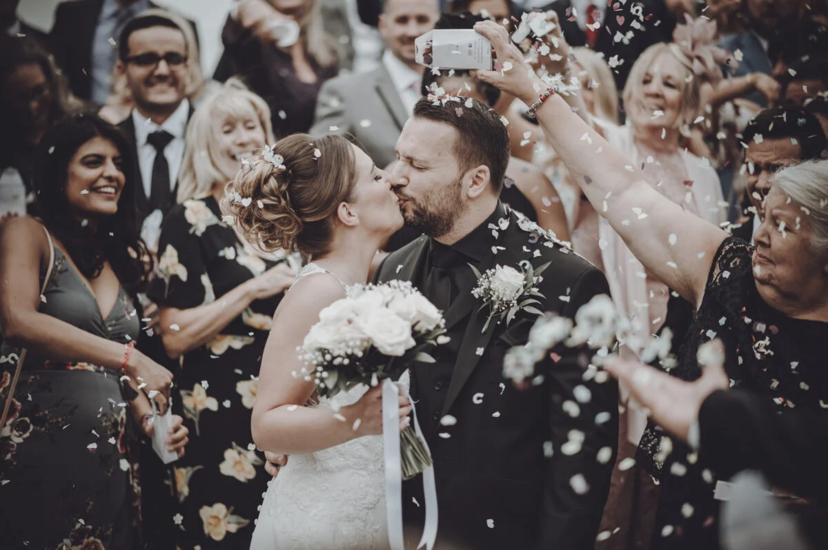 A bride and groom kissing in front of confetti.