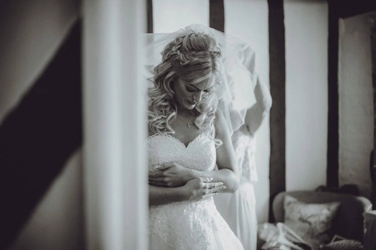 A bride is getting ready for her wedding in a black and white photo.