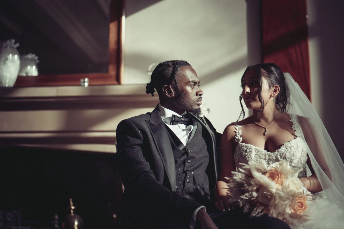A bride and groom sitting in front of a fireplace.